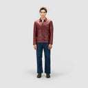 Man wearing rust red leather jacket, structured fit, front zip closure, slip-in pockets, paired with blue jeans