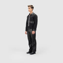 Side view of man wearing black winter jacket for men with leather cuffs, collar, and patch pocket detail, leather pants.