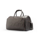Brown travel duffle bag featuring embossed TZÁR logo, silver-tone zippered compartments, adjustable straps, and handles