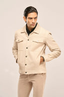 Man wearing a beige ribbed corduroy jacket with metal buttons, flap chest pockets, and jetted side pockets.