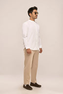 Side view of man wearing white mandarin collar shirt with full sleeves and relaxed fit, paired with beige pants and loafers.