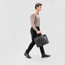 Man in glossy light brown lyocell shirt for men featuring button loops & full sleeves, black pants and bag, side profile.