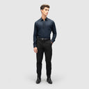 Man in navy blue shirt for men with full sleeves, glossy finish, and button loops, paired with black pants and shoes.