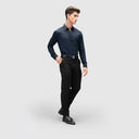 Side view of man in glossy navy blue shirt for men with full sleeves and button loops, black pants, and shoes.