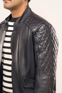 Close-up of man wearing navy blue soft leather jacket, featuring quilted shoulder detail and snap-button collar.