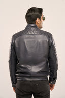 Man wearing navy blue soft leather jacket, sleeves, quilted back yoke with TZÁR logo patch, regular fit, rear profile.