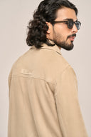 Close-up side and back view of man in beige suede leather jacket featuring ​​TZÁR logo patch on back yoke.