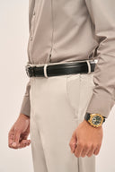 Close up of man wearing gray pleat shirt with full sleeves and buttoned cuff, paired with light trousers and black belt.