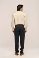 Man in butter yellow mandarin collar shirt back view with subtle loop-and pleat yoke and full sleeves, worn with black pants.