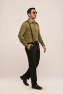 A man in side view wearing a dark olive men's shirt with full sleeves and button loops, paired with suspenders and pants.