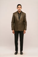 Man wearing dark olive genuine leather blazer, notch collar, horn buttons, patch pockets, paired with black pants