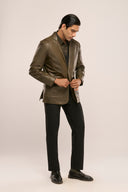 Man wearing dark olive leather blazer, side profile, structured shoulders, full sleeves, paired with black pants