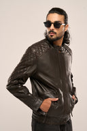 Close-up of man wearing black soft leather jacket, featuring quilted detail, pockets, and full sleeves, wearing sunglasses.