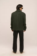 Man wearing dark green suede leather jacket back view showing suede finish, full sleeves, and ​​TZÁR logo patch, black pants.
