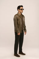 Man wearing dark olive leather jacket for men, side view, structured fit, full sleeves with zips, worn with black pants