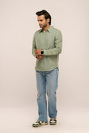 Side view of man in sage green linen shirt showing relaxed drape, full sleeves and cuff detail, paired with jeans.