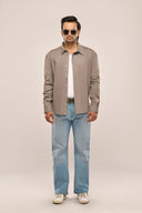 A man in a relaxed fit grey men's shacket featuring full sleeves, drop shoulders, and silver snap buttons, paired with jeans.