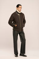 Man wearing coffee brown fur leather jacket for men with plush collar and adjustable buckles, zipper front, side profile.
