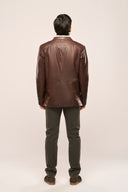 Back view of man wearing coffee brown leather blazer, TZÁR logo patch, structured shoulders, and full sleeves, brown pants
