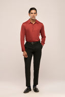A man in a slim-fit, rust red lyocell shirt with full sleeves and unique button loop details, paired with black pants & shoes.