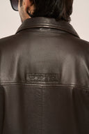 Close-up back view of man wearing black leather jacket for men, featuring structured back panel and TZÁR logo patch