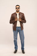 Man holding the coffee brown genuine leather Biker Jacket he is wearing, which is paired with a t-shirt and a pair of jeans