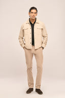 Man in beige ribbed corduroy jacket with flap and jetted pockets, beige trousers, and brown shoes on a plain light background.