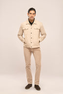 Man in beige corduroy jacket with ribbed texture, flap & jetted pockets, metal buttons, beige pants, and dark shoes.