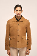 Man wearing suede leather jacket for men in brown with spacious flap pockets, collar, horn buttons, and full sleeves.