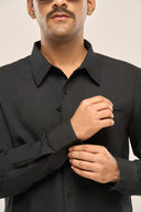 Close up of a man in black chambray shirt featuring full sleeves and button cuffs.