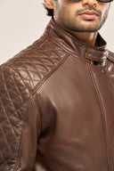 Close-up of man wearing coffee brown soft leather jacket, featuring quilted shoulder detail and snap-button collar.