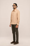 Man wearing slim fit beige monochrome shirt with monotone side panels and full sleeves, paired with brown trousers.