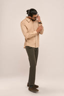 Man wearing slim fit men's beige shirt showcasing monotone side panels and full sleeves, paired with brown trousers.