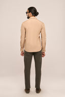 Man wearing slim fit monochrome shirt in beige, back profile with full sleeves and clean lines, paired with brown pants.