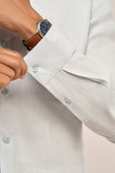 Close-up of man wearing light blue linen shirt featuring full sleeves and 3-button cuffs.