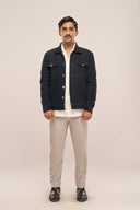 Man wearing navy corduroy jacket over white shirt with beige pants and black boots.