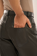 Back of men’s black leather trousers worn by man with his hand in one of the two back pockets added for utility