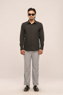 Man wearing a charcoal black pleat shirt with front pleat detailing, full sleeves, and a slim fit, paired with grey trousers.